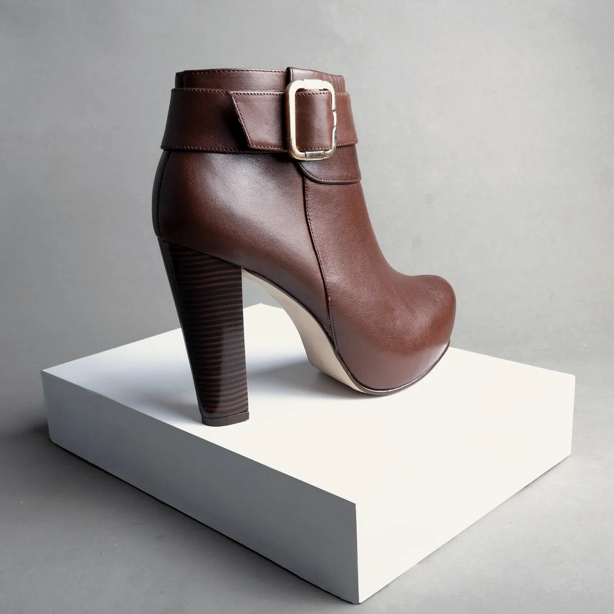 Bota de couro marrom sobre um bloco branco